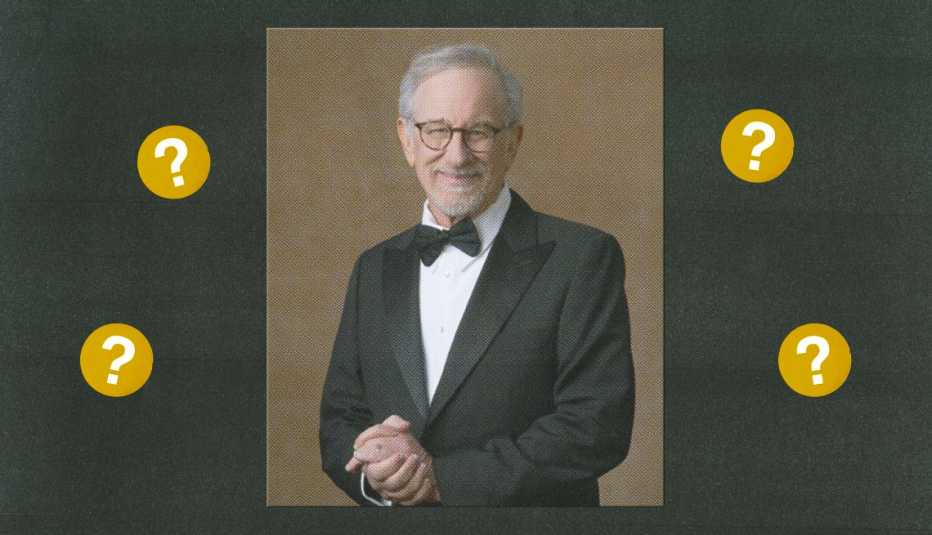 steven spielberg in tuxedo surrounded by gold circles with question marks in them