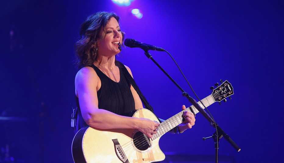 Sarah McLachlan holding guitar and singing into microphone