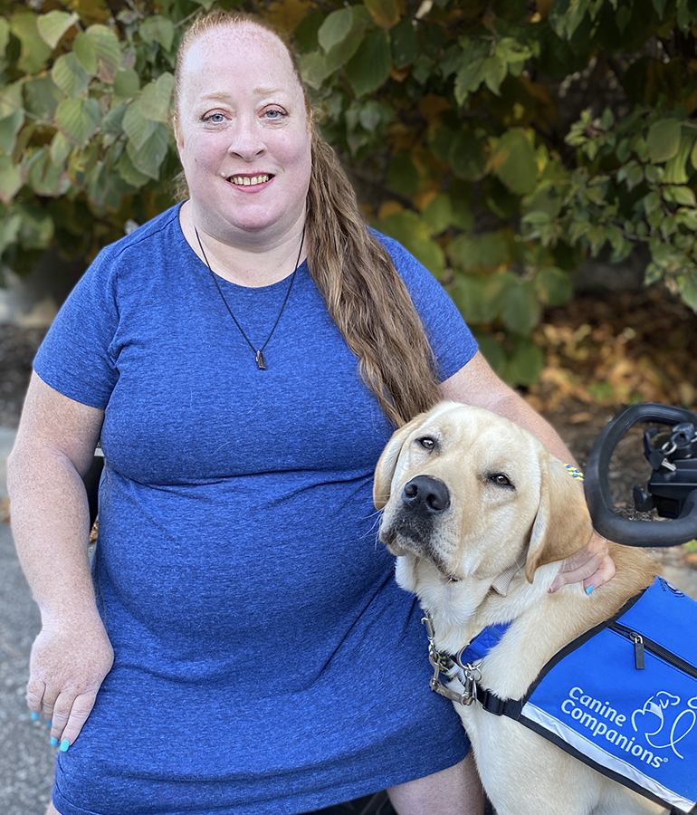 Annmarie Snow-Matera next to service dog, Malfoy, wearing blue Canine Companions vest