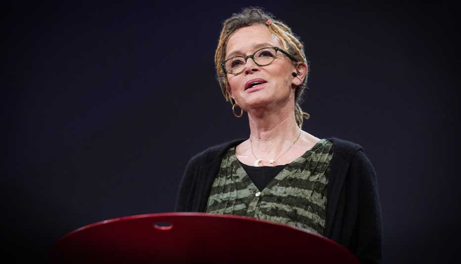 anne lamott standing at podium, speaking into a headset microphone