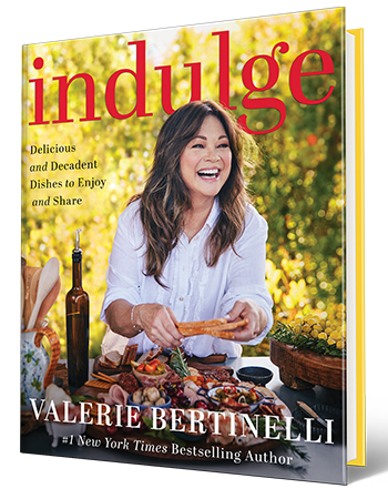 Book cover with Valerie Bertinelli behind spread of food on it; words say Indulge, Delicious and Decadent Dishes to Enjoy and Share, Valerie Bertinelli