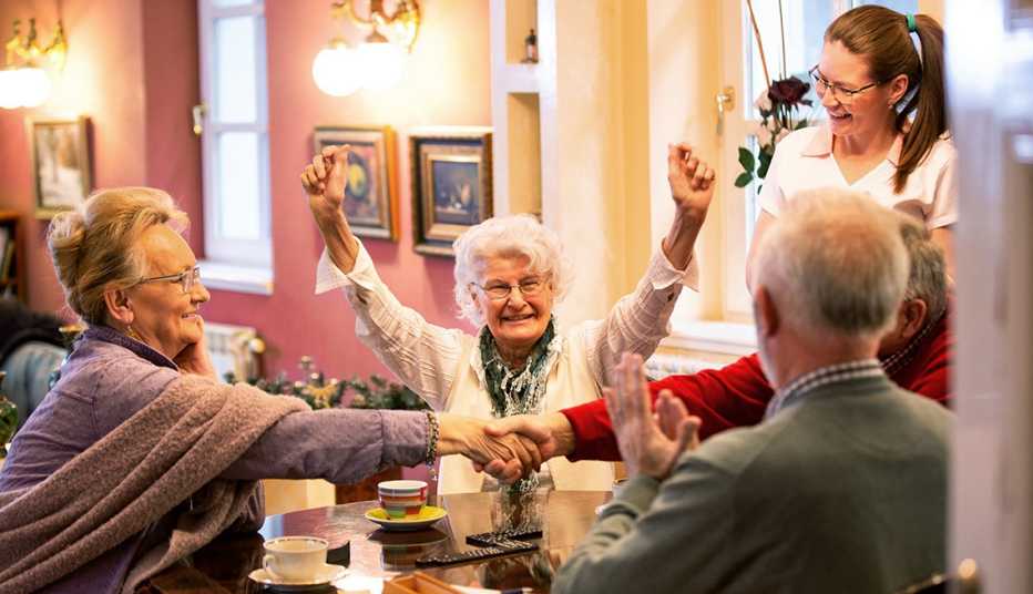 Residents of a group care home playing a game together while a female aide looks on