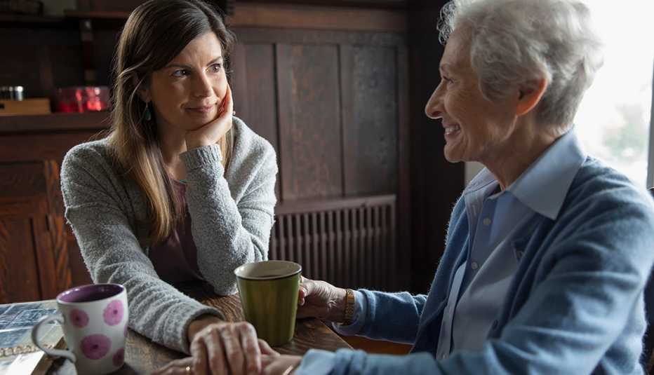 Adult woman having coffee with her mother at the kitchen table