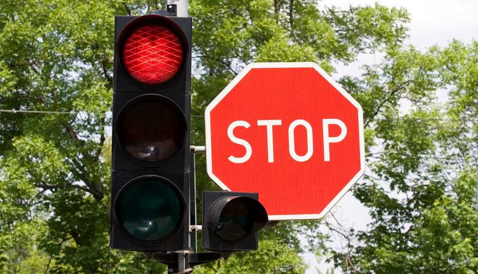 A red traffic light and a red stop sign next to each other
