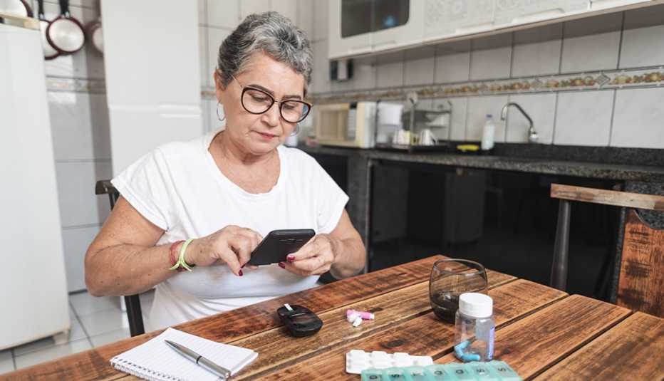 a woman looks at her phone while taking her medication