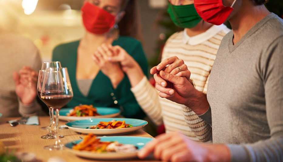 Family in face masks eating Thanksgiving dinner