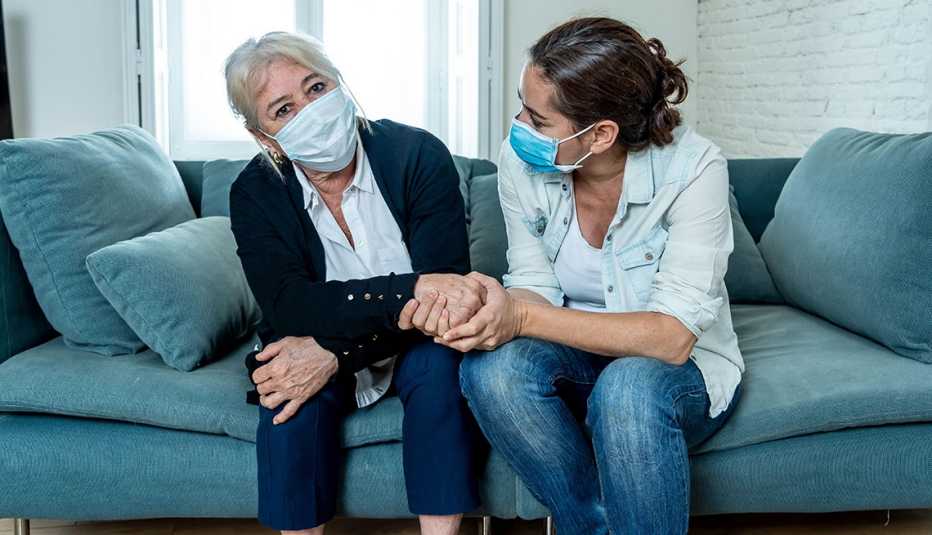 A woman and her mother on the couch both wearing face masks