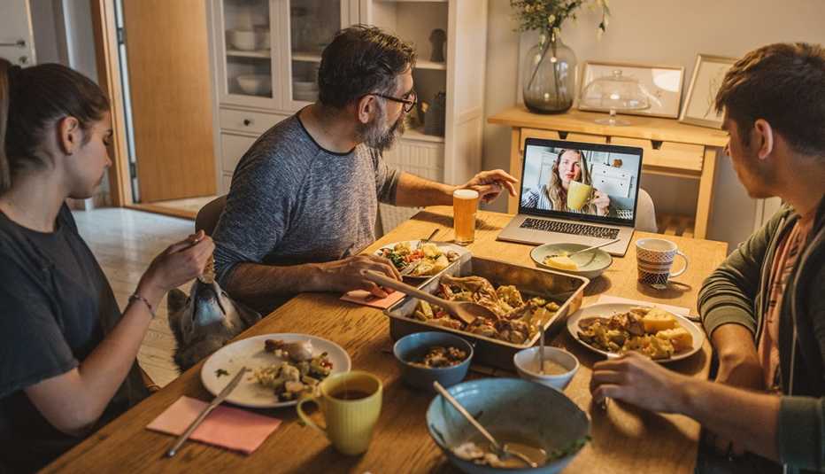 Dad and two teenage children having dinner while video chatting with a relative