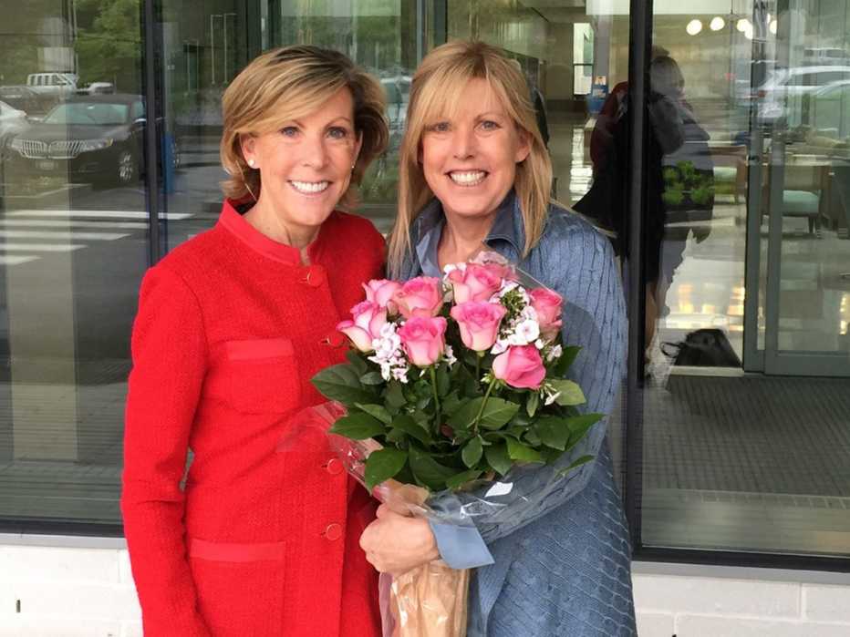 kathy guisti and her twin sister karen andrews holding a bouquet of pink roses