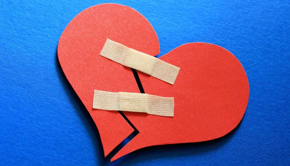 Two halves of a broken paper heart mended with two band aids