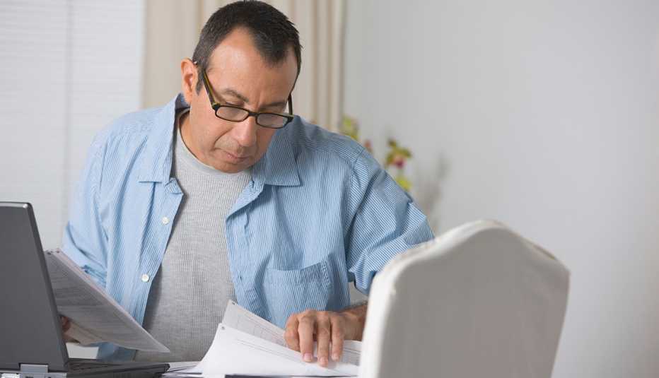 Man sitting behind a computer, looking at  insurance claim paperwork