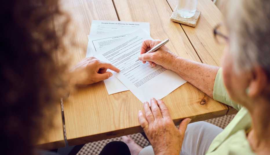 a woman signs documents with a financial adviser in her home