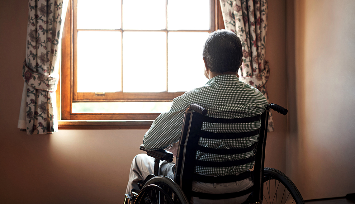 Rearview shot of a lonely senior man in an assisted living facility looking out the window while sitting in his wheelchair