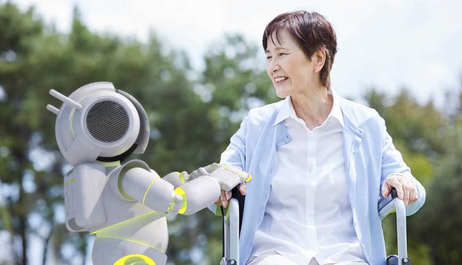 a robot next to a woman in a wheelchair wearing a blue sweater on a sunny day