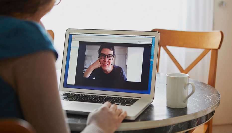 A woman sitting at table using a laptop on a video call with another woman