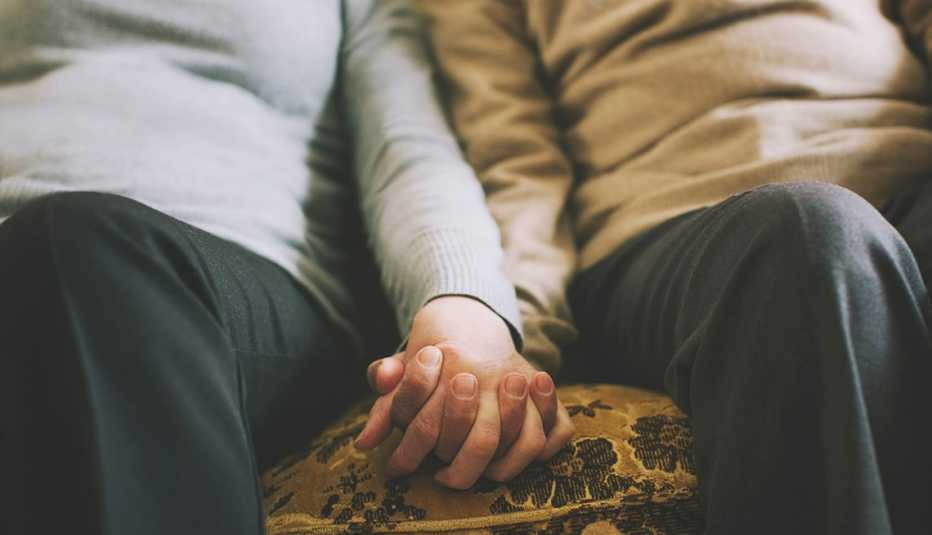 Couple holding hands on a couch