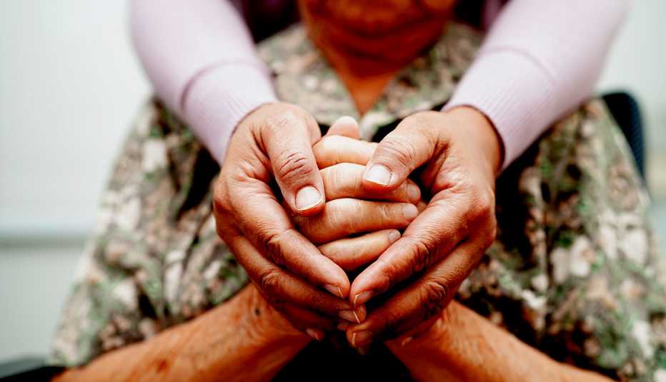 Caregiver holds hands with an elderly female patient.