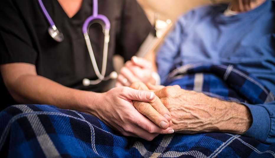 Close up of a hospice nurse holding the hands of one of her patients