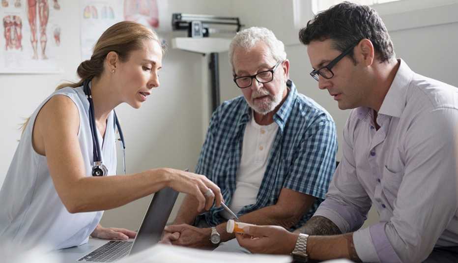 A doctor, elderly patient and caregiver reviewing prescription information