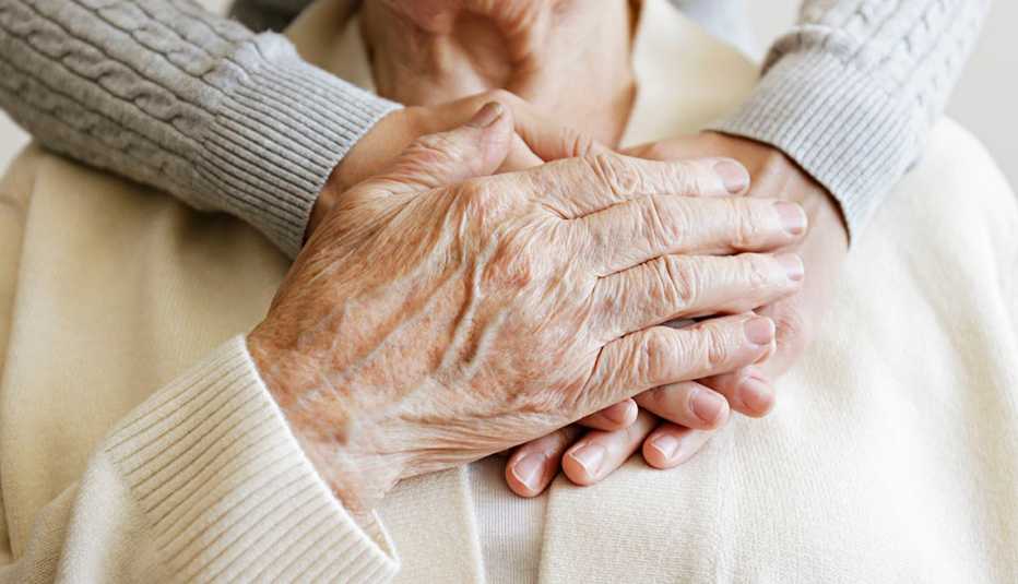 older woman holds hands of her caregiver
