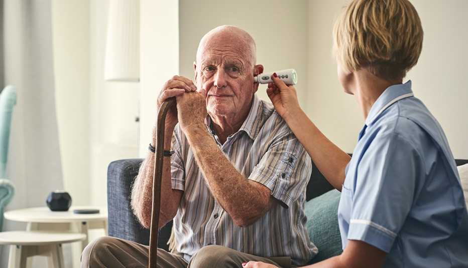 An in-home caregiving aide taking her patients temperature to screen him for the coronavirus