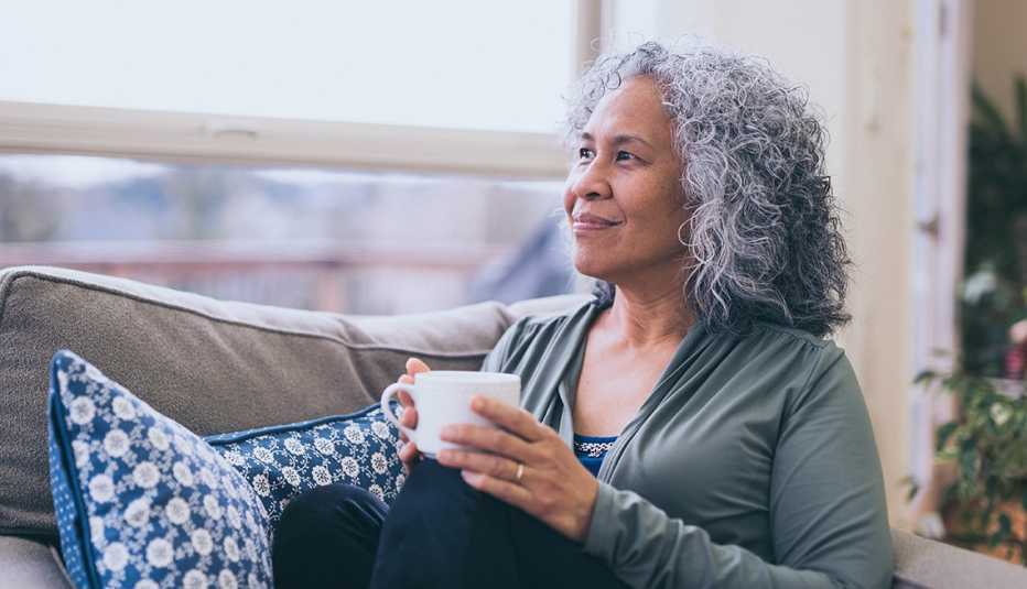 Woman sitting on the couch with a cup of coffee looking calmly out the window