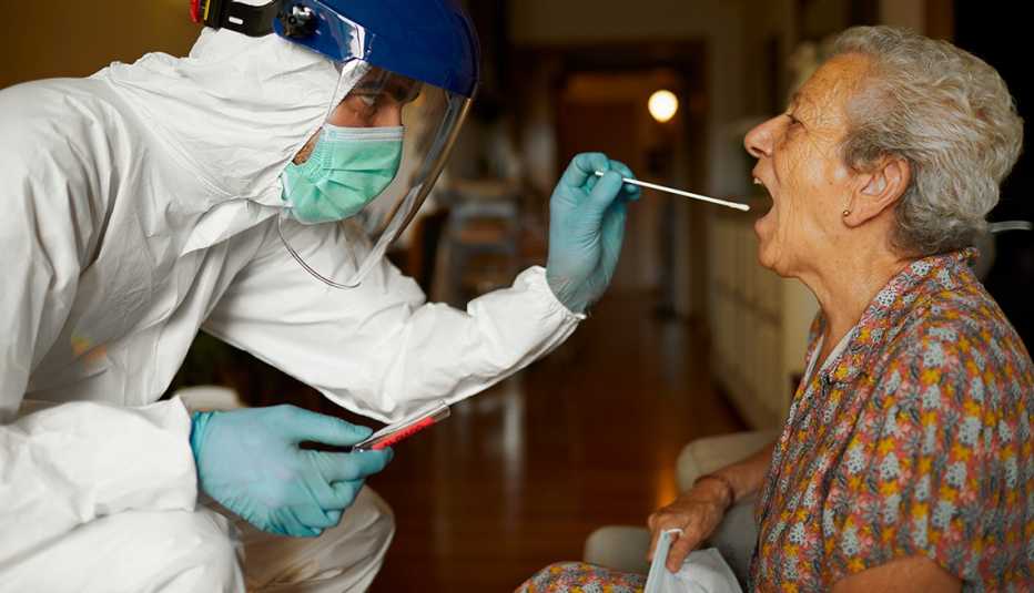Health care worker in PPE giving a COVID-19 test to a woman