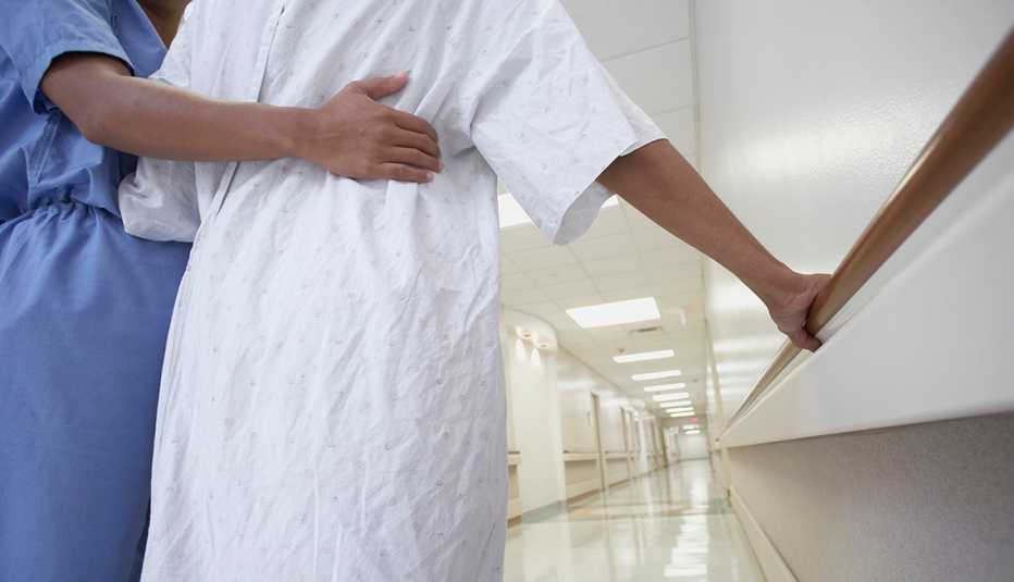 A nurse helping a nursing home patient walk down the hallway