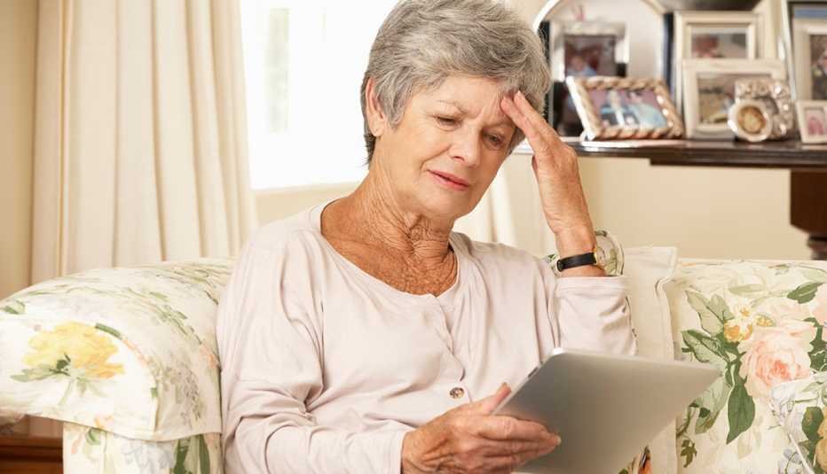 Woman in a nursing home holding a tablet and looking frustrated