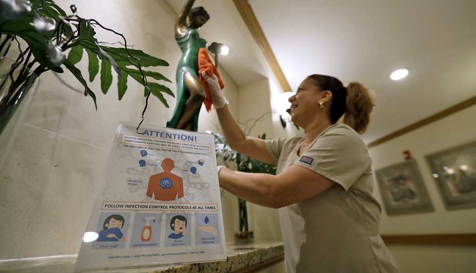 A female Environmental Services member cleans behind an infection control warning poster at a rehabilitation center
