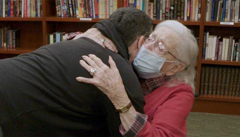 a nursing home resident wearing a face mask hugs her daughter