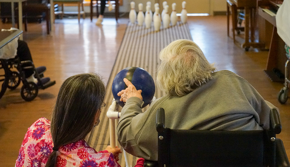 nursing home resident janice whitley bowling with the help of  an aide