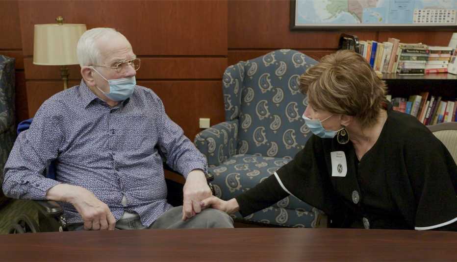 a nursing home resident holding his wife's hand during a visit