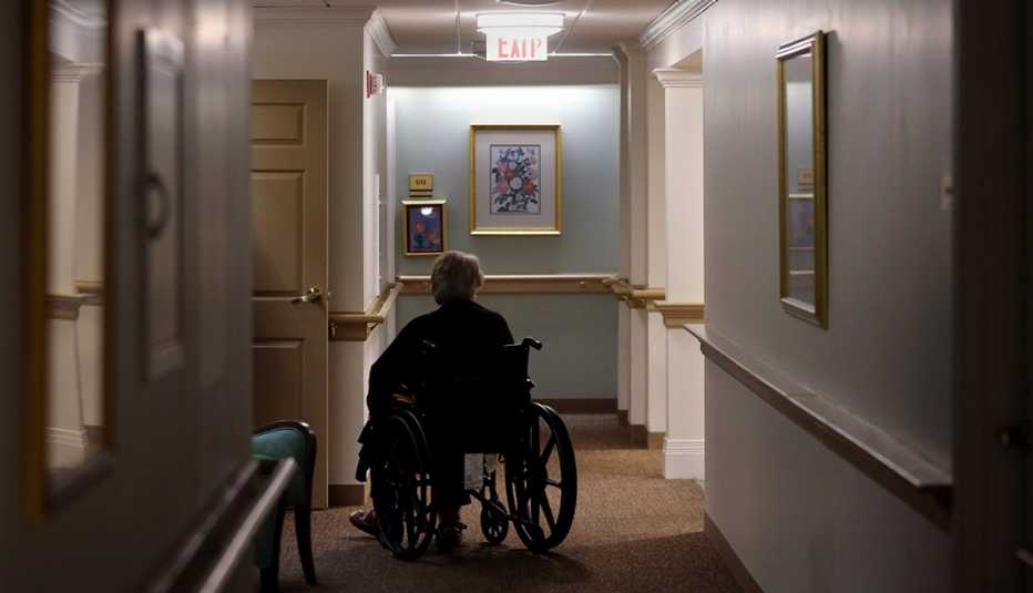 A man sitting in a wheelchair in the hallway of a nursing home
