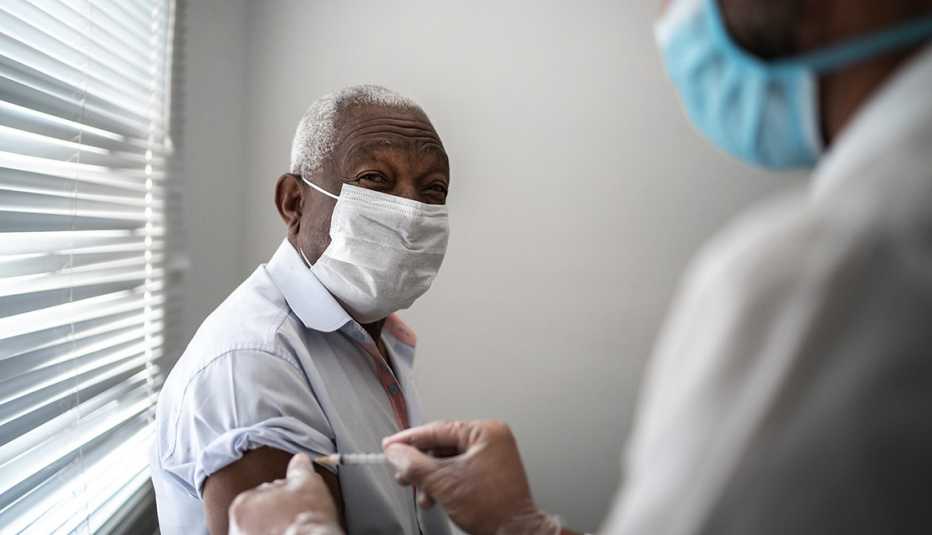 A nurse giving a male nursing home resident a vaccine shot in the arm