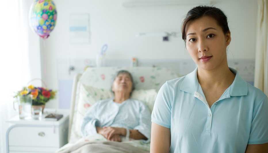 A woman standing with a female patient sleeping behind her