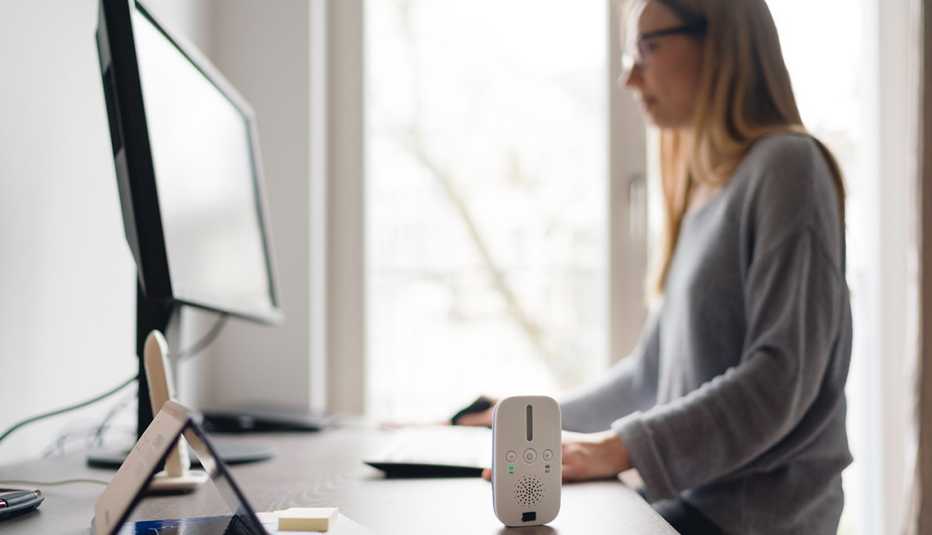 Woman working at home with an audio baby monitor on her desk