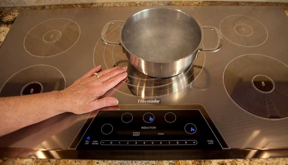 Someone places their hand on an induction cooktop to show it doesn't get hot