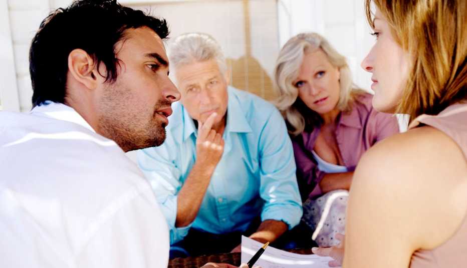 Adult brother and sister reviewing a caregiving document with their parents.