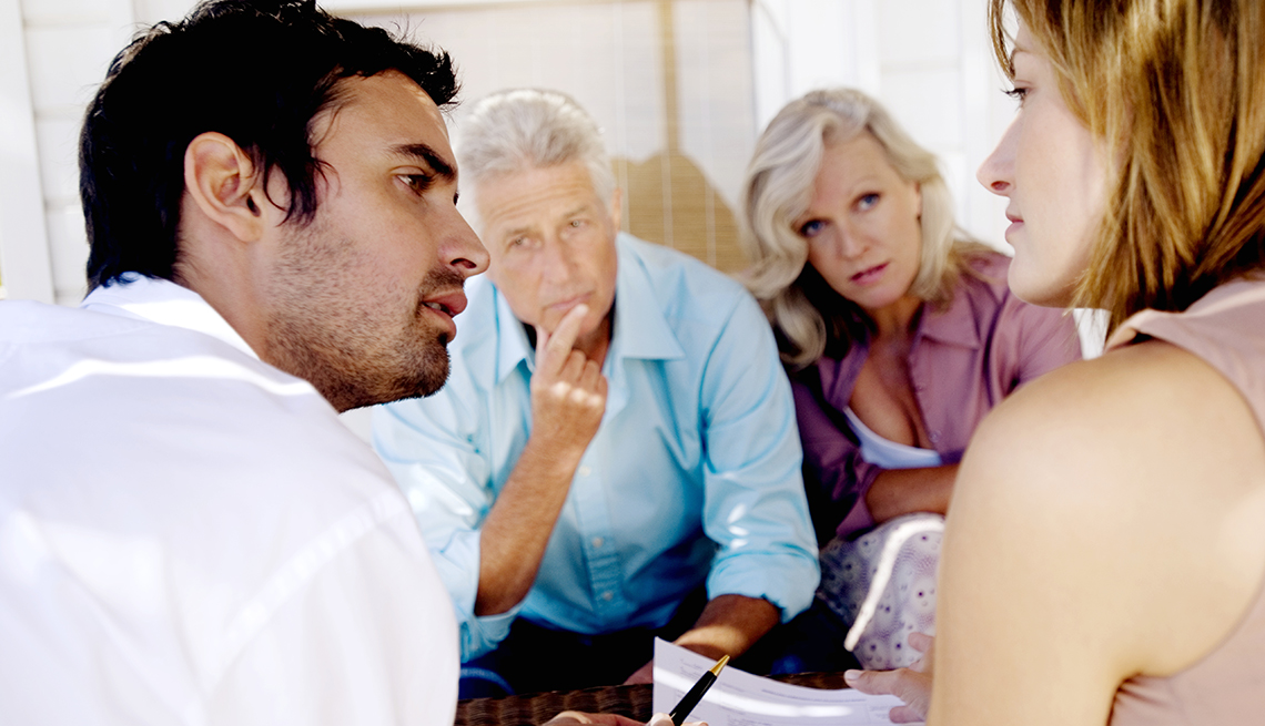 Adult brother and sister reviewing a caregiving document with their parents.