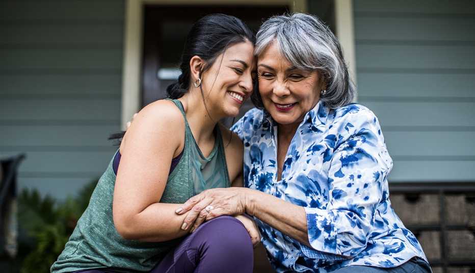 Senior woman and adult daughter embracing and laughing on porch