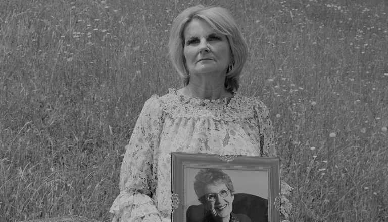 a woman holds a framed picture up of another woman