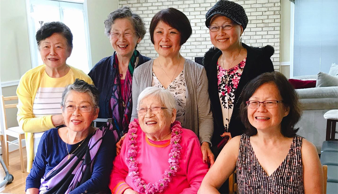 Seven women pose in front of an 80th birthday cake