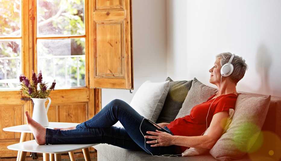 A woman sitting on her sofa listening to a podcast