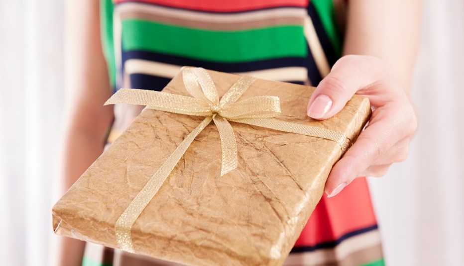 close shot of a woman holding out a gift wrapped book as a present