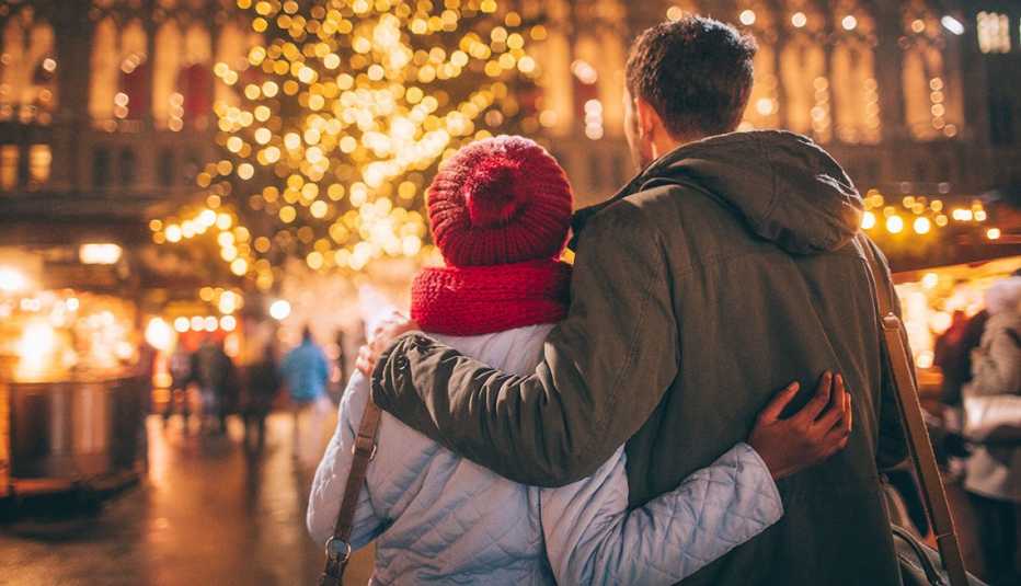 a couple holding each other at a christmas market in a city