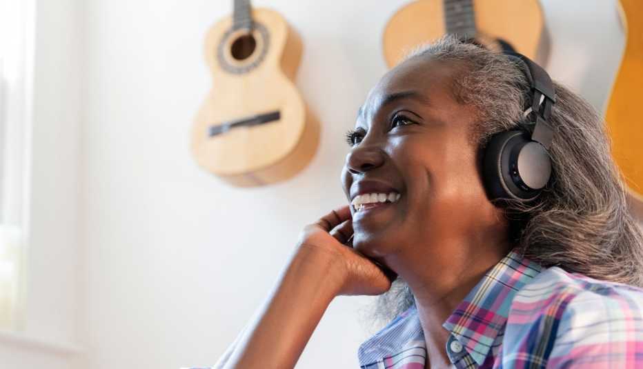 woman listening to music on headphones with guitars hung on the wall behind her