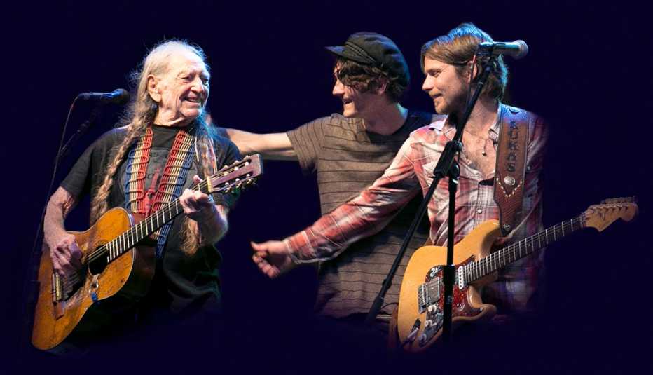 Willie Nelson on stage performing with two of his children. 