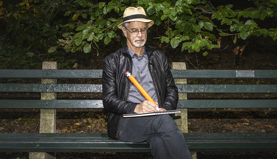 photo of garry trudeau sitting on a park bench with an oversized pencil in hand drawing a cartoon