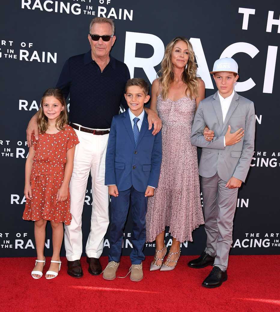 kevin costner his wife christine baumgartner and their three kids stand on the red carpet at an event